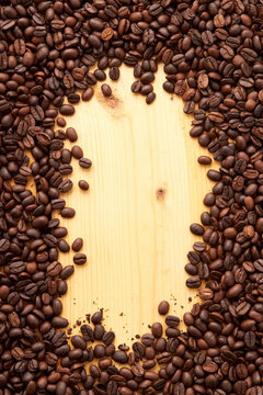 Top view of roasted coffee beans texture background on flat lay in vertical with wooden board free space in center. pattern for design menu drink. coffee beans frame.