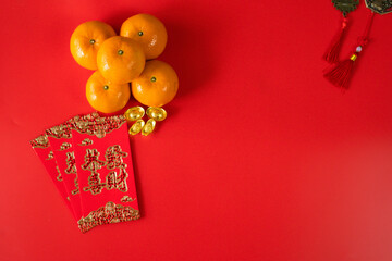 flatlay design for chinese new year concept with red envelope orange and gold on red background(non english text is GONG XI FA CAI mean wishing you enlarge your wealth)