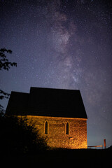 Medieval stone chapel under stars lit by torchlight. 