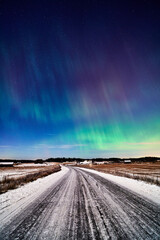 Northern lights over road and fields in winter