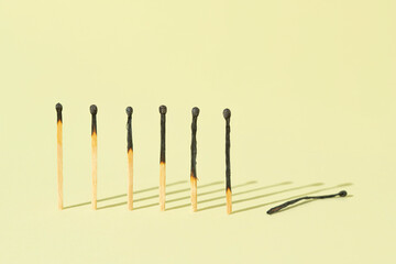 Burned matches on a pastel yellow background with copy space. Stress and burned out problem minimal creative surreal concept. 