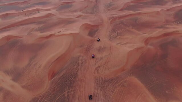 A drone flies over quad bikes driving through the sand dunes of the desert in the United Arab Emirates
