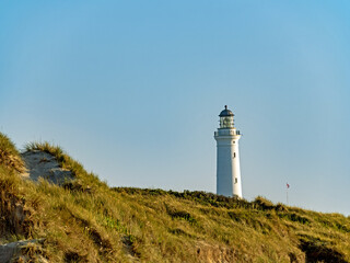 Über die Dünen der dänischen Nordseeküste ragt der Leuchtturm von Hirtshals - 690529408