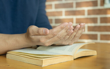 close up young man hand gesture to pray while reading holy book in home for ramadan tradition al and cultural of muslim religion concept