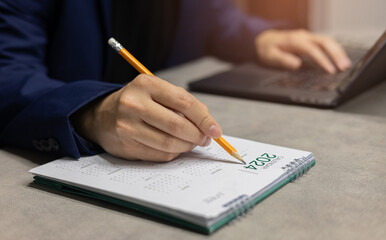 close up manager man hand use pencil to write on calendar to booking about date and time of meeting...