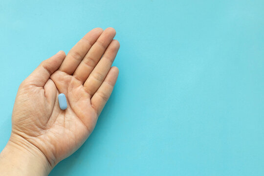 close up top view man hand with Prep pills on blue background with space for world aids day and hiv prevention concept