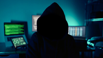 Mysterious hacker sitting at desk in dark atmosphere. A computer programmer or hacker. Anonymous...