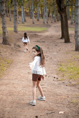 Full length image of a cute two sisters walking in the park, in fall time. 