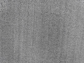 Close-up black and white image of a textured fabric surface, showcasing a rough, almost woven appearance with small, closely spaced lines