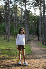 Cute shy little girl in a elegant clothesposing in park.