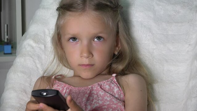 Kid Watching TV, Child Using Remote Control on Sofa, Girl Browsing Internet on Television Set on Coach in Living at Home, Family