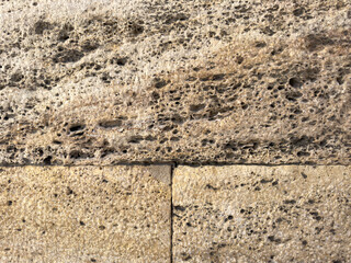 Close-up of a weathered rock wall background with detailed texture and cracks. Suitable for graphic design and background use.