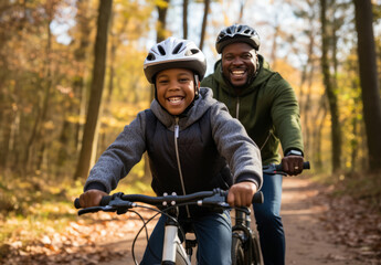 Black man and son joyfully riding bicycles in a park or forest in fall