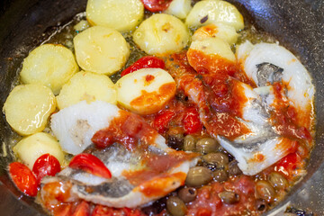 sea bass fillet in tomato sauce with potatoes, olives and capers