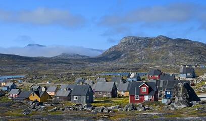 colorful houses and mountain peaks in  the rocky  fishing village of nanortalik, in southern greenland, on a sunny summer day © Nina