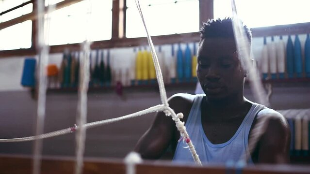 Man, loom and manual production at clothing factory, manufacturing and craftsmanship. Black male person, warehouse and weaving thread or cotton industry, textiles and fabric designer or treadle