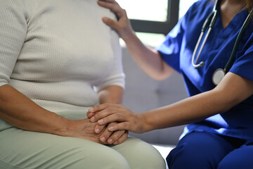 Cropped shot of doctor holding hands of senior patient for giving support, empathy and...