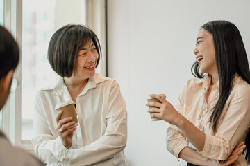 Cheerful diverse colleagues having fun on a coffee break in office.