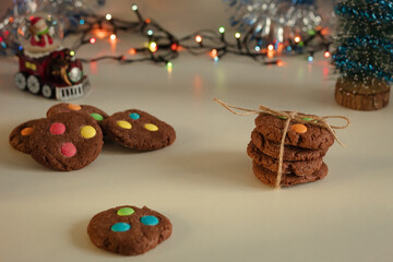 Homemade brown cookies folded in a column and tied with a rope on a white table. Background blurred colored bokeh. New Year's atmosphere. Festive mood.