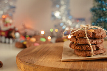 Cookies folded and tied with rope on paper and wooden table. There is tinsel and garland in the...