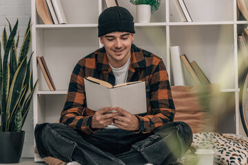 young man at home reading a book in autumn winter clothes