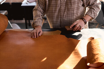 man tries to maintain the integrity of the leather fibers. close up cropped photo, artisan lightly brushes the leather surface.