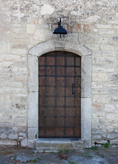 Fototapeta na wymiar Ancient wooden door with street lamp on whit brick wall.
