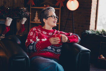 Photo of peaceful minded grandmother sit chair hold cacao mug imagination inspiration magic christmas time indoors