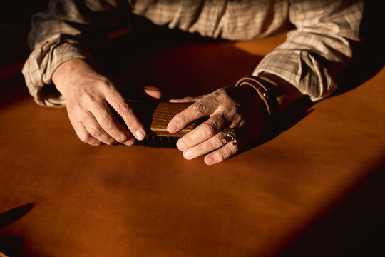 old man using brush to clean the surface of cloth, close up cropped photo.man holding brush, thinking about futer steps of creating goods. focus on arms
