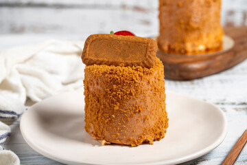 Biscuit cake. Delicious cream cake on a white background. Cake with fruit inside and biscuits on the outside