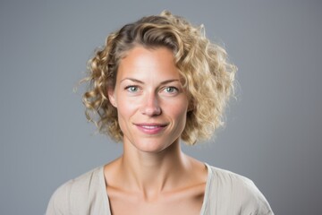 Portrait of a beautiful young woman with blond curly hair over grey background