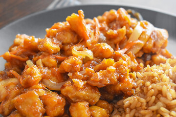 Sweet and sour chicken with egg fried rice on a plate. Chinese food.