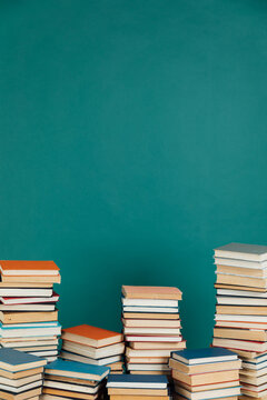 Stacks of old educational books in library on green background