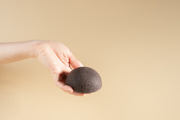 Konjac facial sponge in hand, a round cleansing accessory for facial hygiene