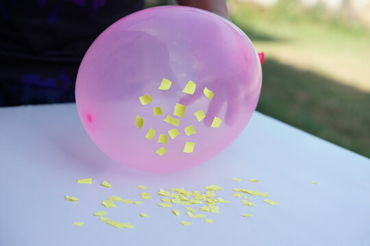 Closeup hand hold pink balloon to do science experiment about static electricity from balloon and pieces of paper. Concept, Science lesson, fun and easy experiment. Education. Teaching aids.     