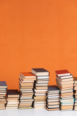 Stacks of educational books in library on orange background