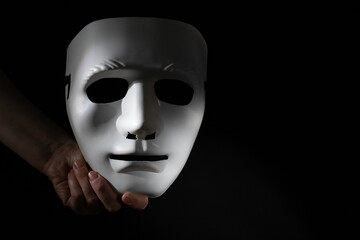 White mask in hand on a black background, Privacy protection, white mask concept, secure online identity