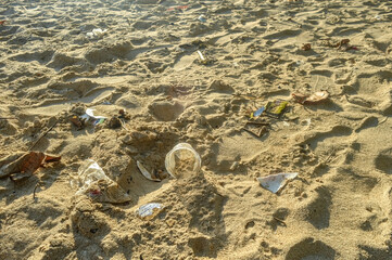 The beach sand is dirty because of plastic mineral water cups