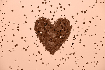 Heart made of shiny small decorative hearts. Trendy color of year 2024 - Peach Fuzz.