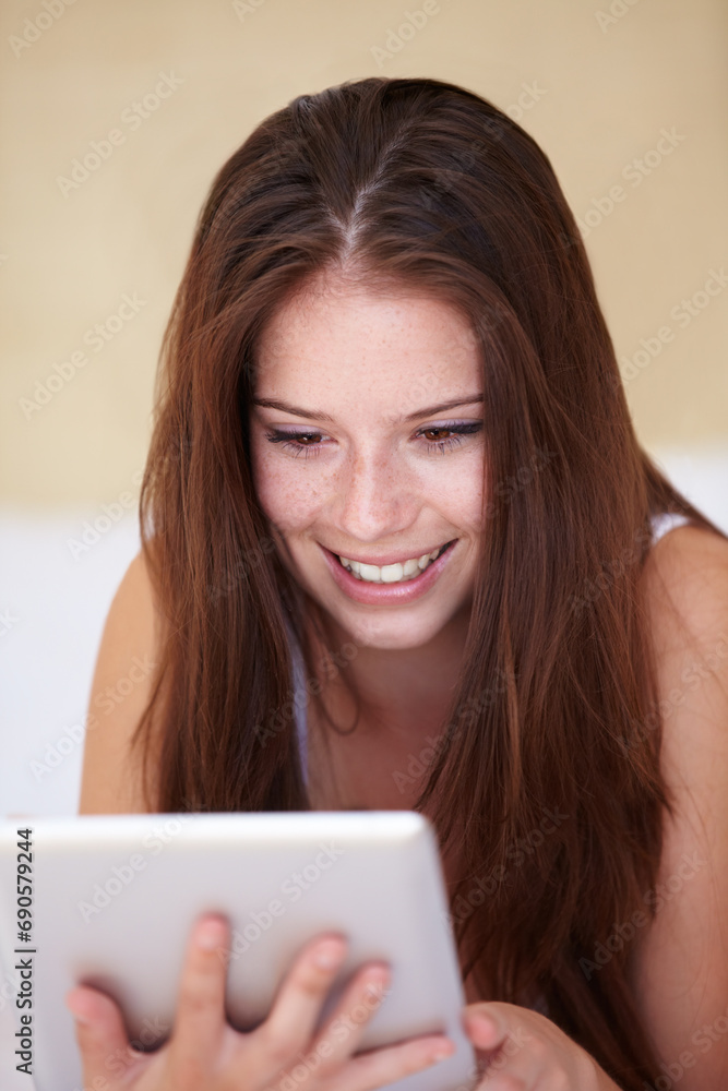 Poster Face, tablet and social media with a woman in the bedroom of her home to relax while browsing the internet. Smile, technology and app with a happy young person lying on a bed in her apartment