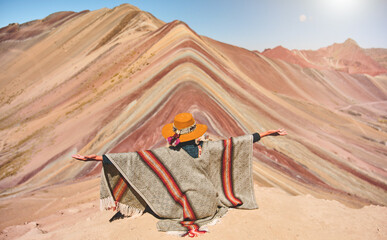Panoramic view, Young girl sitting in front of the Vinicunca Rainbow Mountain, Peru South America
