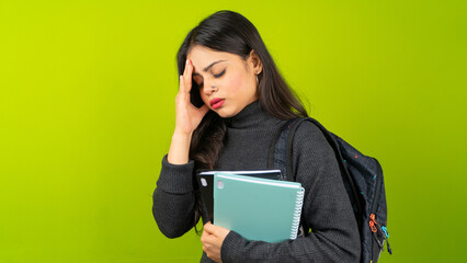 Young Indian student woman wearing backpack and holding books, unhappy, sad, or stressed college girl isolated over green screen chroma key background