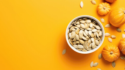 White bowl of pumpkin seeds with mini pumpkins on a yellow backdrop, capturing the essence of autumn.