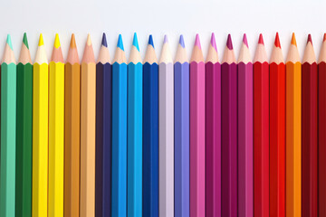Close-up of vibrant colored pencils aligned on white background, perfect for design and art themes.