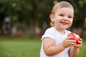 Toddler boy eating an apple and smiling