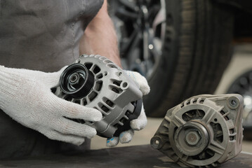 A generator for an automobile engine on the car mechanic's desktop. A specialist examines the new...