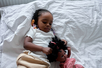 nice pretty girl is lying in bed hugging toy doll before going to bed Children sleep wake mode...