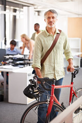 Fototapeta na wymiar Mature man, business and bicycle in office with portrait and manager of sustainable company. Ceo, boss and job with eco friendly commute in morning with smile in a creative agency of a professional