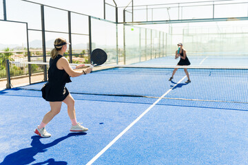 Happy women playing padel and working out