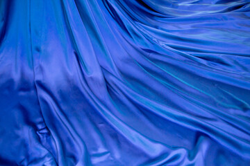 The fabric is a shiny blue color arranged in beautiful waves. Design backgrounds textures interior.